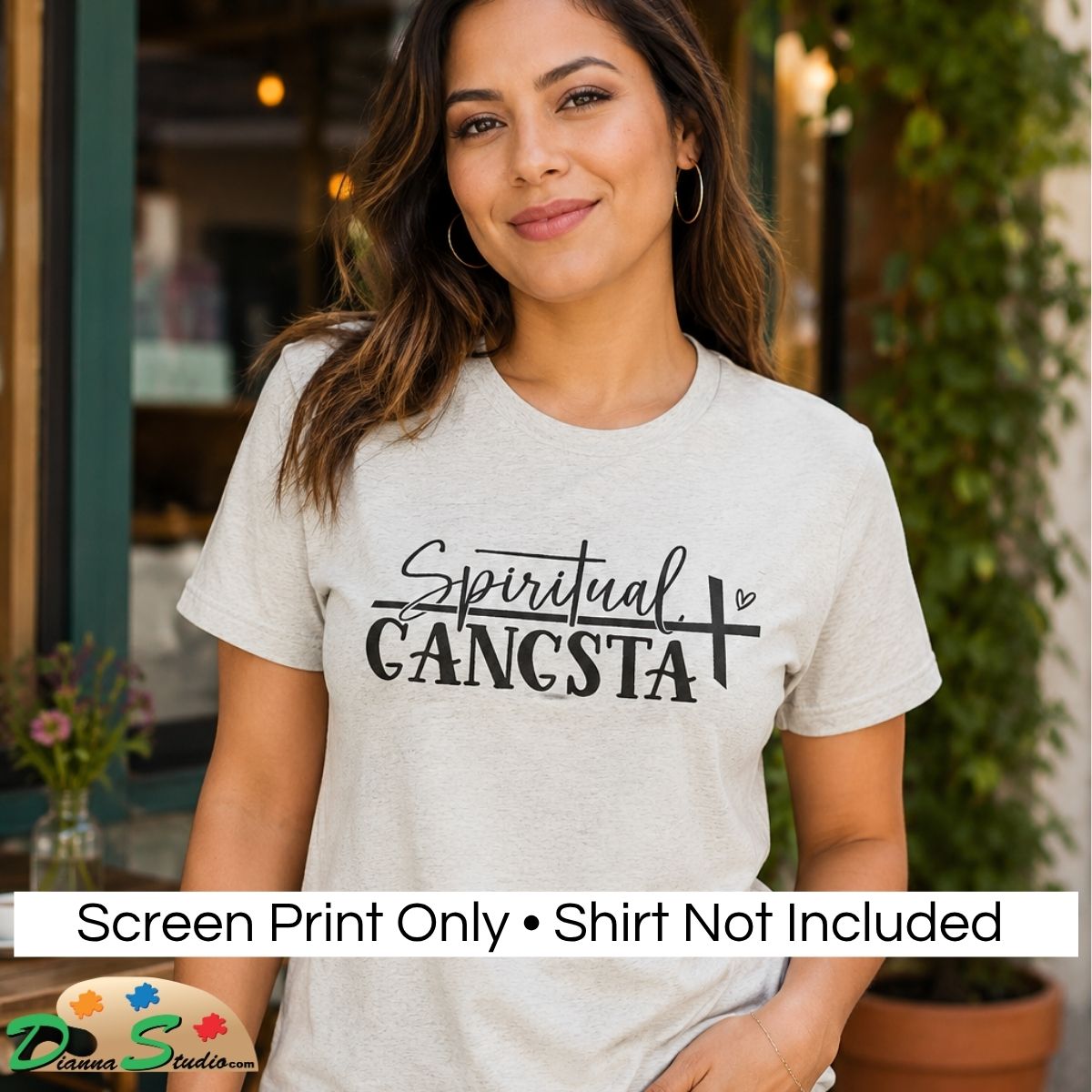 A woman wearing a light heather gray graphic t-shirt with the text 'Spiritual GANGSTA' printed in black. A white banner at the bottom reads 'Screen Print Only • Shirt Not Included' with a 'DiannaStudio' logo in the corner, set against a blurred storefront background.